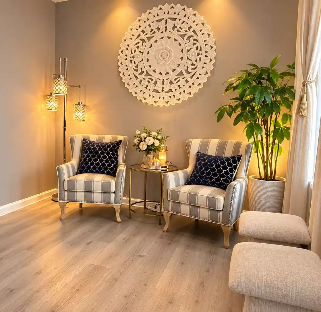 Front lounge with two striped armchairs and a potted plant by a sheer-curtained window
